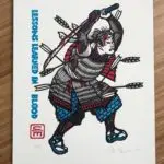 A Samurai, shot with seven arrows, holds a broken and bloodied sword overhead while he continues battle