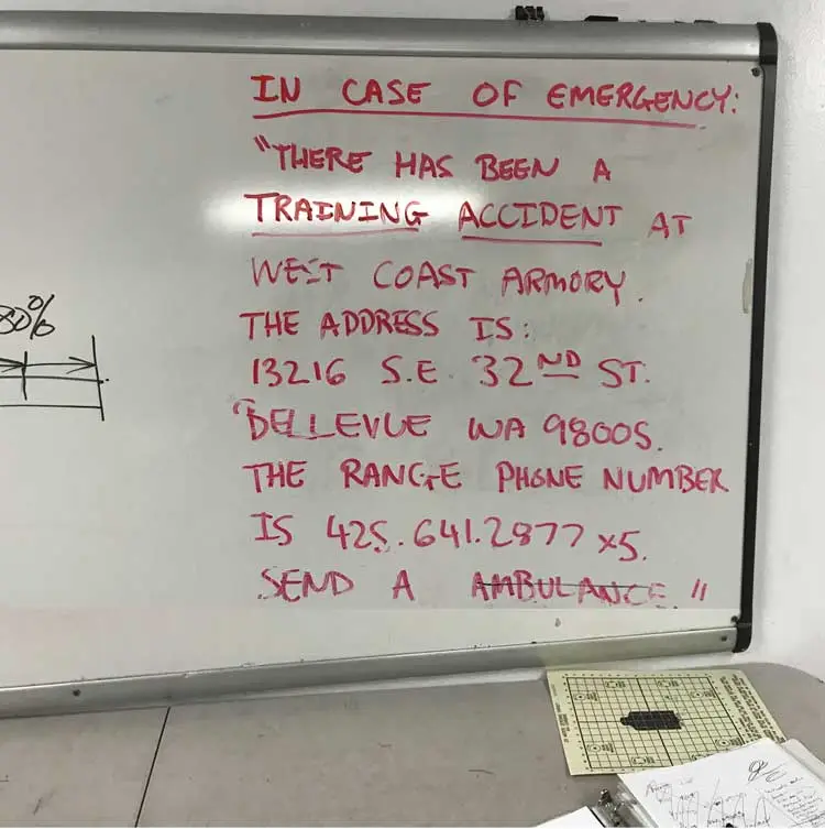 A white board showing the Range directions for calling 911 in the event of a training accident, including the address and phone number