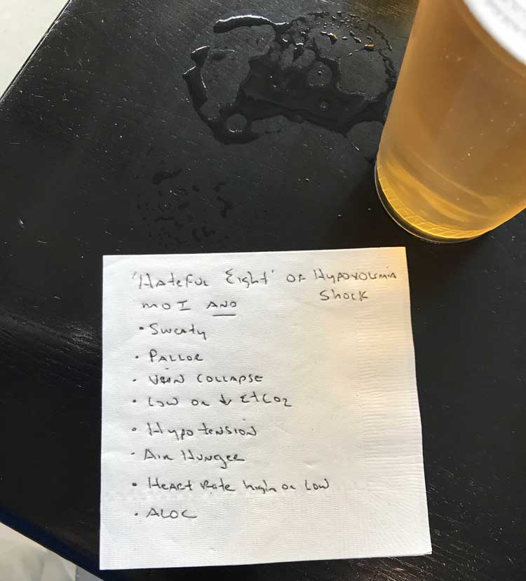 A bar napkin, sitting next to a beer, listing the hateful eight signs to look for before administering prehospital blood in a trauma patient