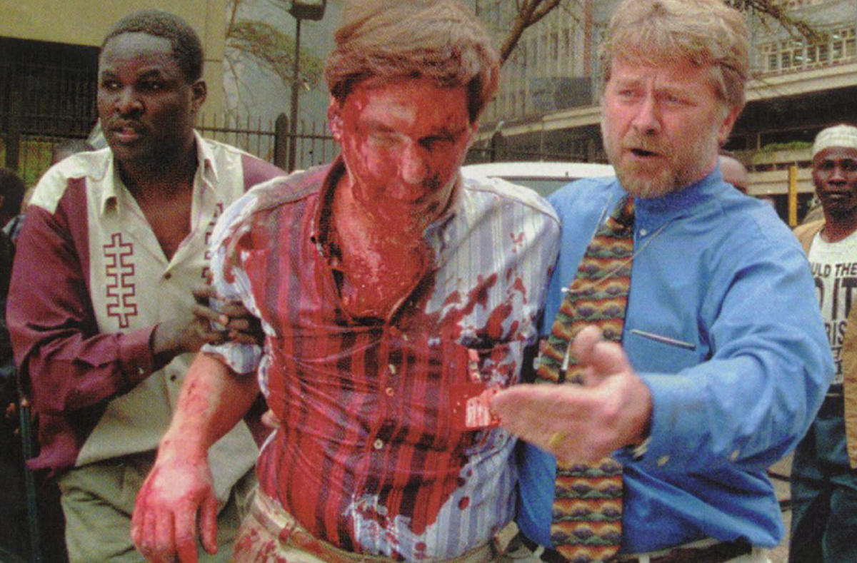 Two office workers help an badly bloodied and injured colleague evacuate the US Embassy in Nairobi in 1998