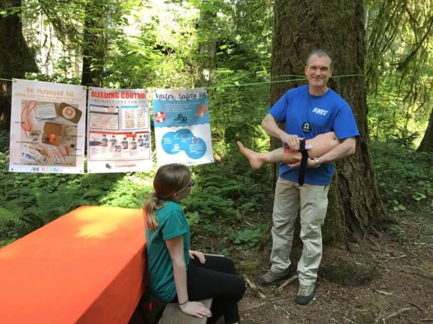 Dr. Shertz in his alter ego as Camp counselor "Omega" stands ruggedly in the woods training Girl Scouts to be prepared for emergency