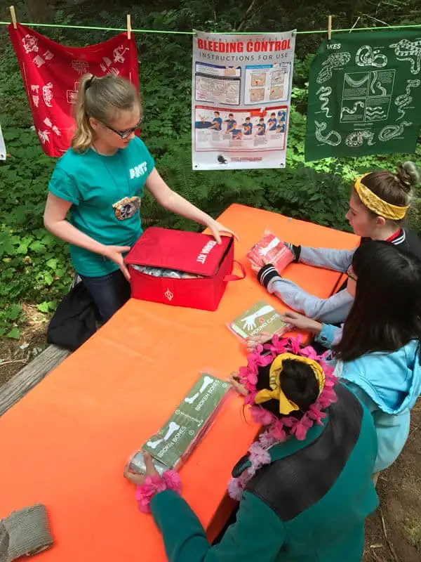 A Girl Scout demonstrates the Tramedic kit to other girls while teaching first aid