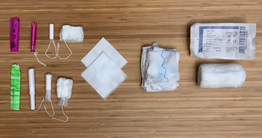 Regular and super-absorbant tampons compared to two 4x4s, their rough equivalent; a roll of training combat gauze; and a roll of Kerlix Gauze.