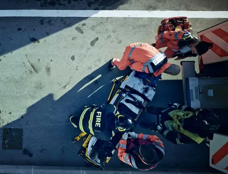 EMS and fire work a casualty strapped to a stretcher