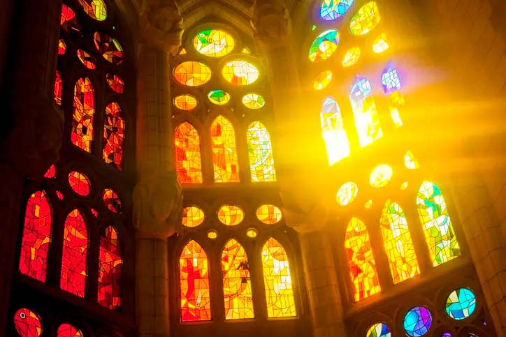 Stained glass window of the Sagrada Familia in Barcelona with sunlight streaming in from the background