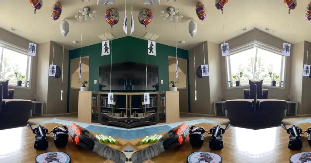 A nerf pistol lays on a table while paper ninjas buoyed by balloons gather for their attack