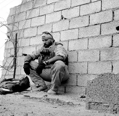 a medic squats along a highly damaged wall in Libya