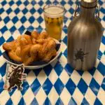 A perfect Oktoberfest display with homemade pretzels, a perfectly poured beer, and a new Crisis Medicine custom Growler on a traditional blue and white checked table