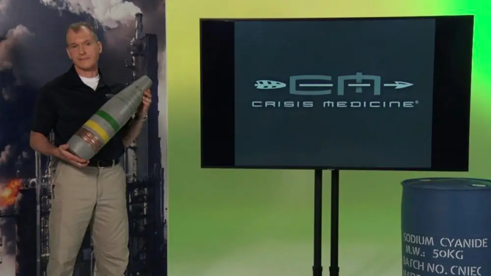 Dr. Shertz holding a VX nerve agent munition prop on the stage of CM's new Tactical CBRN course