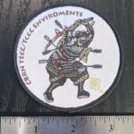 A ~3"woven patch with marrow edge and velcrow backing showing a Samurai in battle, bloodied and shot full of arrows, wearing a gas mask