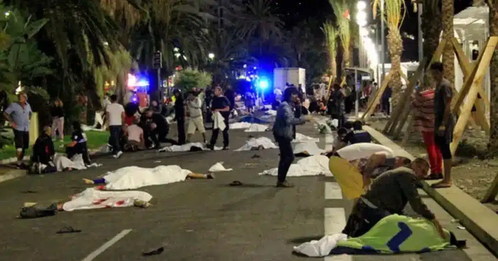 Photograph of the street in Nice where pedestrians were killed an injured by terrorists when they ran down innocent people, the photograph shows bodies scattered in the street covered with white sheets while first responders talk to bystanders & other wounded