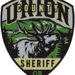 Union County Oregon SHeriff's patch with a moose in the center surrounded by a green mountain and fir trees