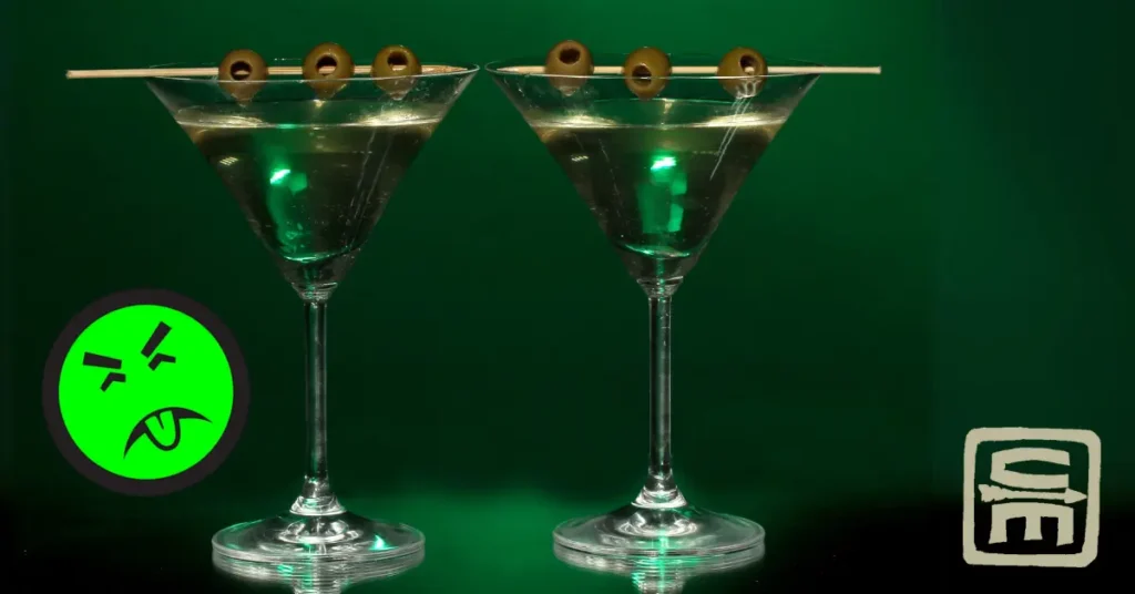 Two ominous looking martini glasses sit with an absinthe green background and a Mr. Yuk sticker