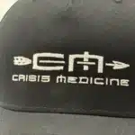 Closeup of the brim of the Crisis Medicine logo'd baseball hat
