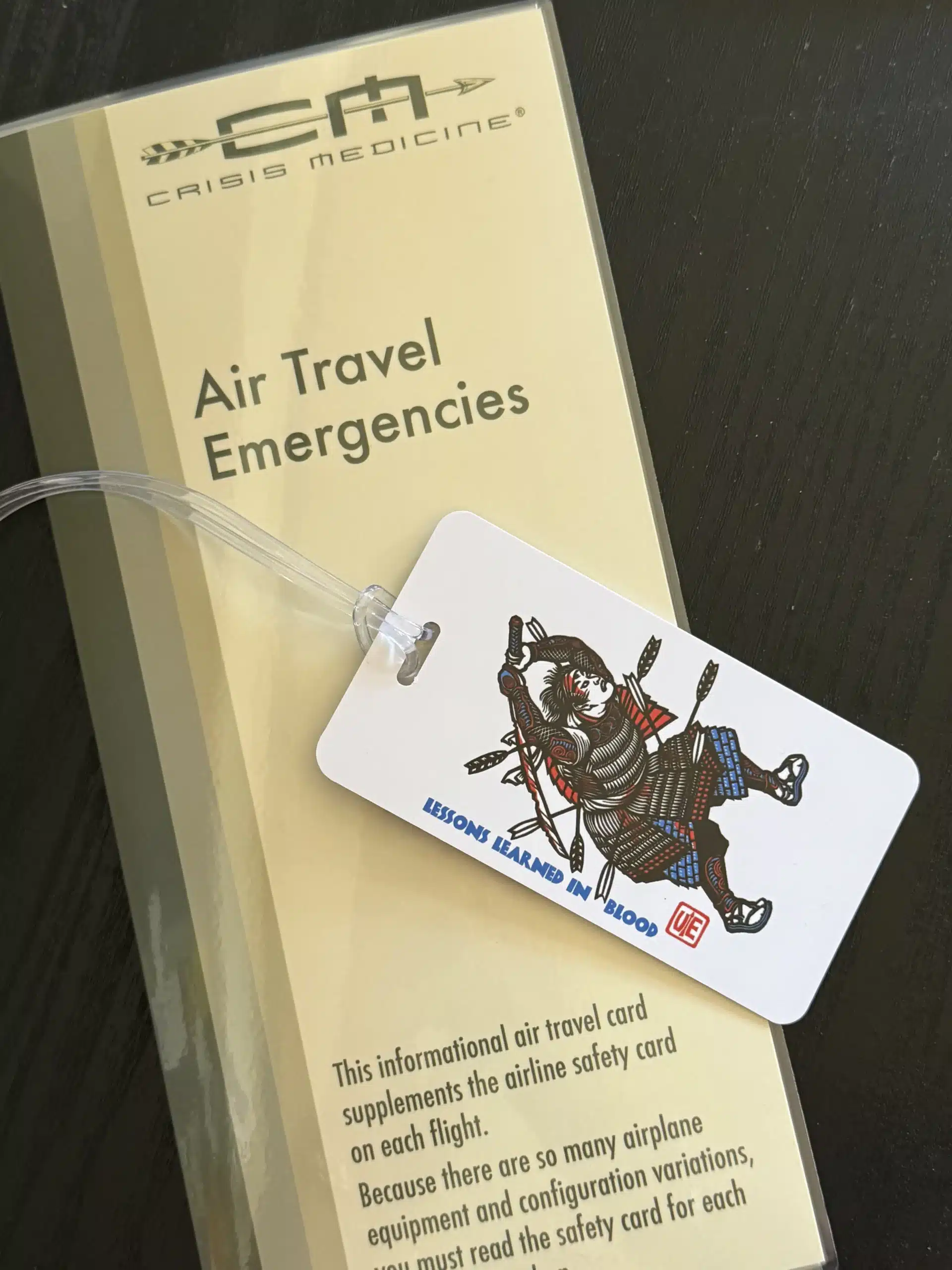 The Crisis Medicine Luggage Tag sitting on a copy the Crisis Medicine Air Travel Emergencies